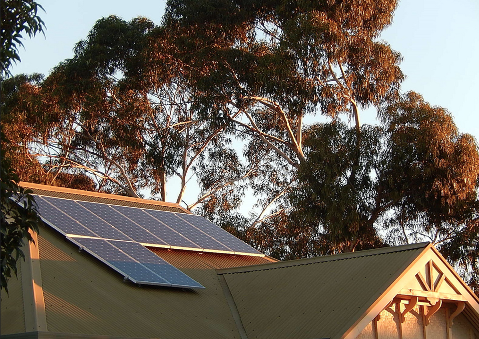 Photo of solar panels on old home with trees in background