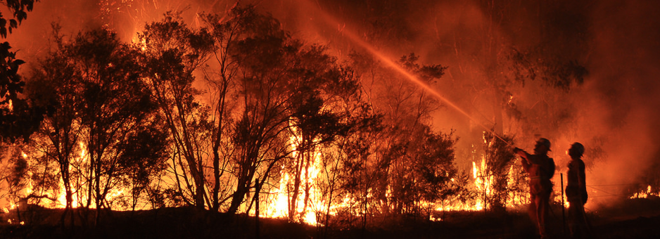 Picture of two firefighters trying to put out a blazing fire at night