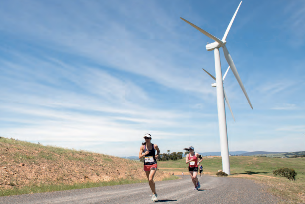 Photo of women running a race next to wind turbines