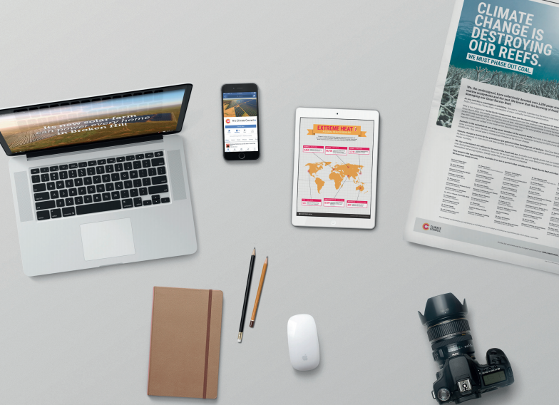 Photo of a desk featuring climate council articles and social media, as well as a notebook and camera