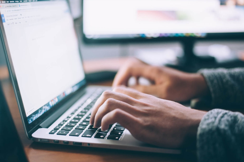 A photo of a person typing on a laptop