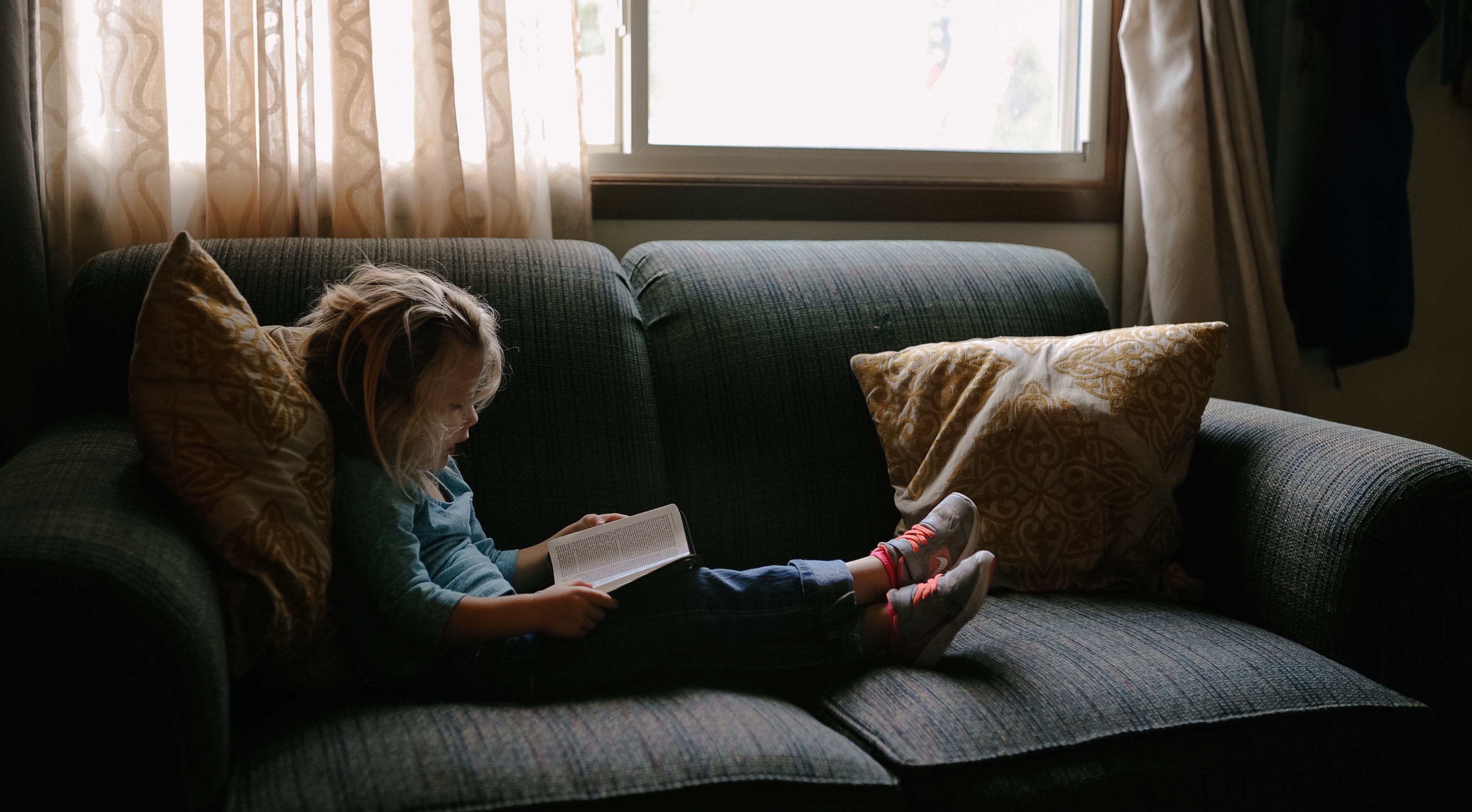 An image of a girl reading a book on a couch