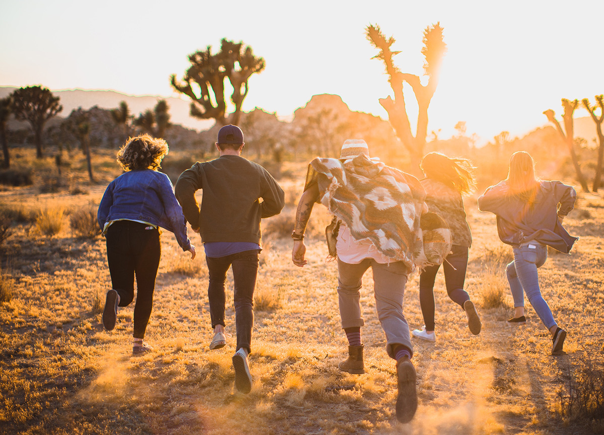 An image of people running in a desert during sunset