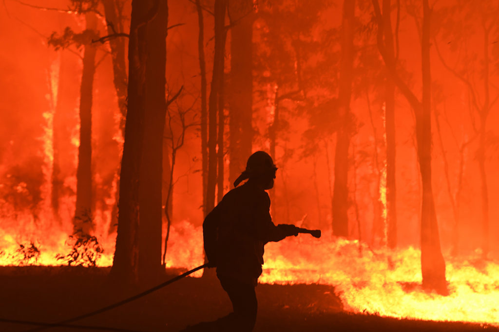 An image of a silhouette of a fire fighter putting out a bushfire.