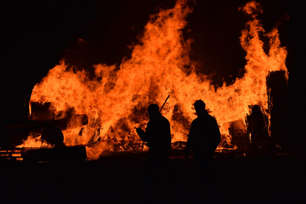 An image of a bushfire with man standing in front.