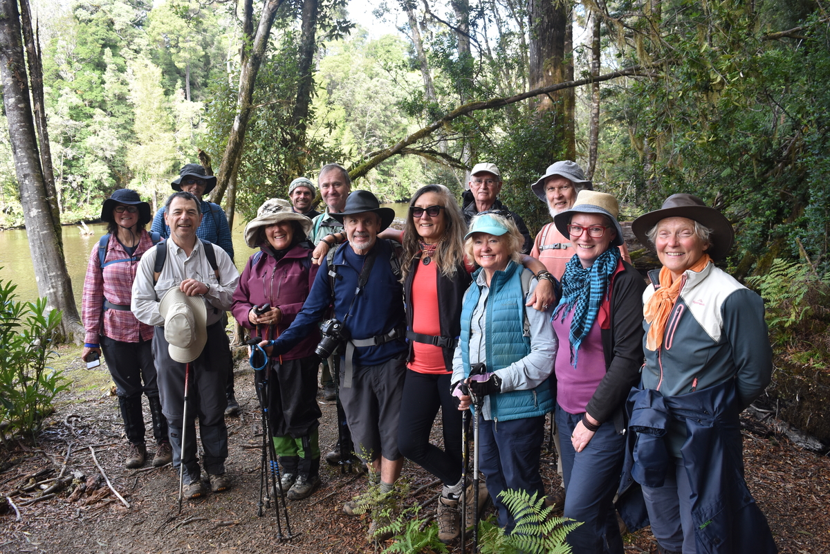 A group of people posing for a photo in front of a lush rainforest