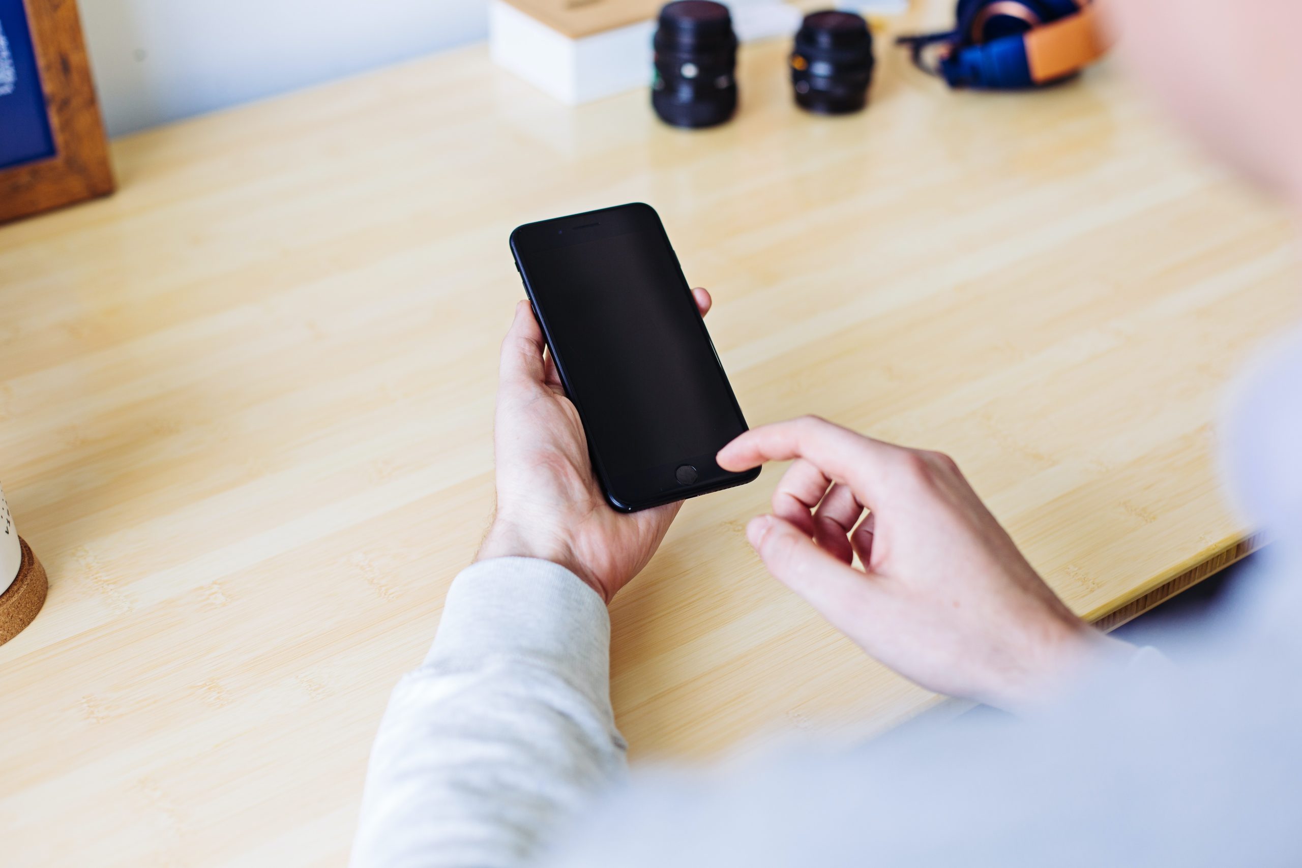 hands holding a mobile phone over a desk