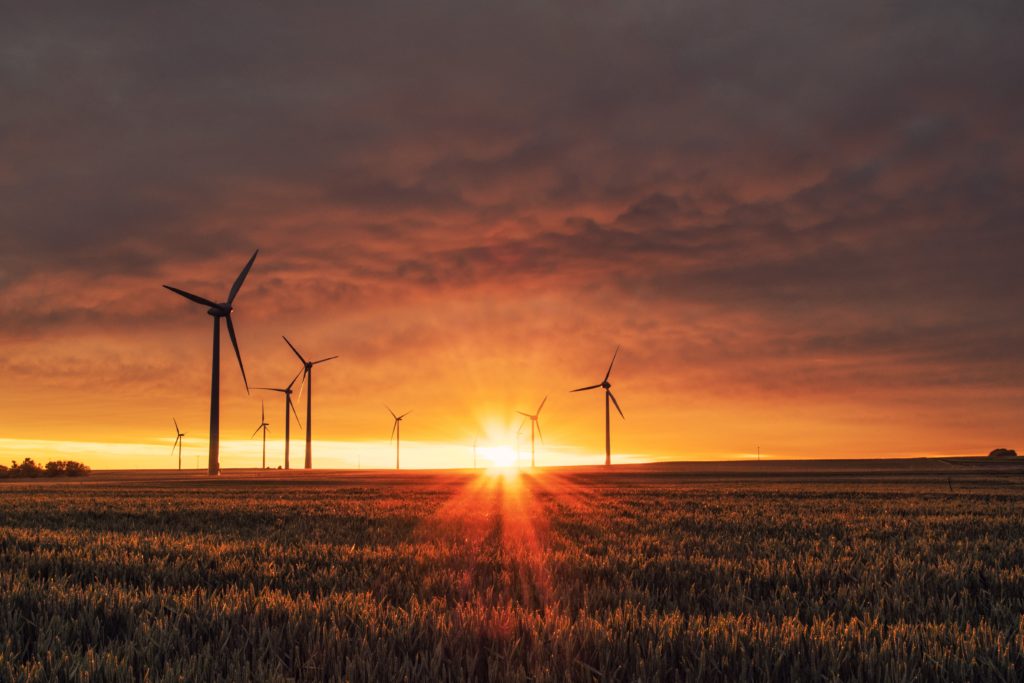 The sun setting on a field of turning wind turbines. Image by Karsten Würth