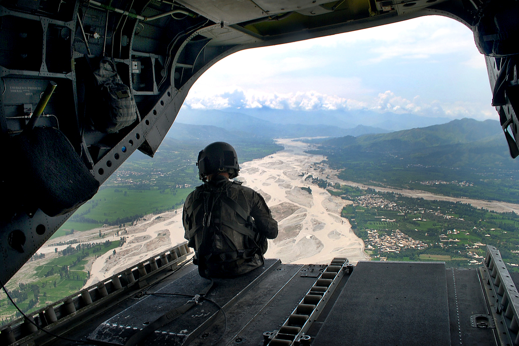 An image of an army person sitting in the back of a plane looking out.