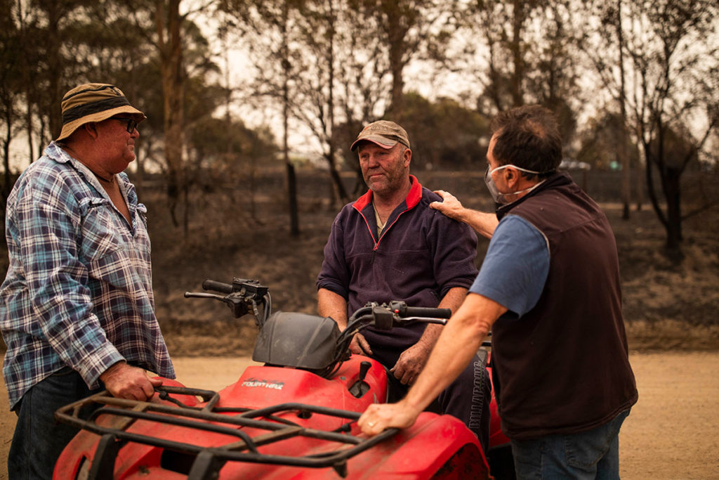 An image of three men around a quad bit with a bushfire smoke haze.