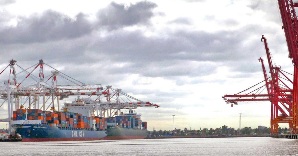 An image of an export terminal with a ship and lots of shipping containers, with some cranes to the right.