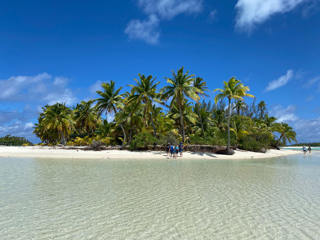 An image of an island in the Pacific with blue sky, palm trees and white sand