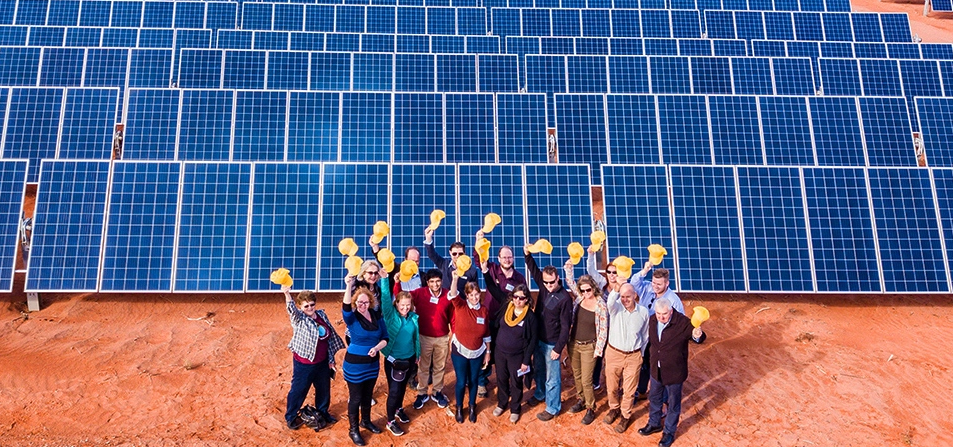 an image of people smiling in front of solar panels with their hats in the air (Photo credit: Andrew Correll) [cropped]