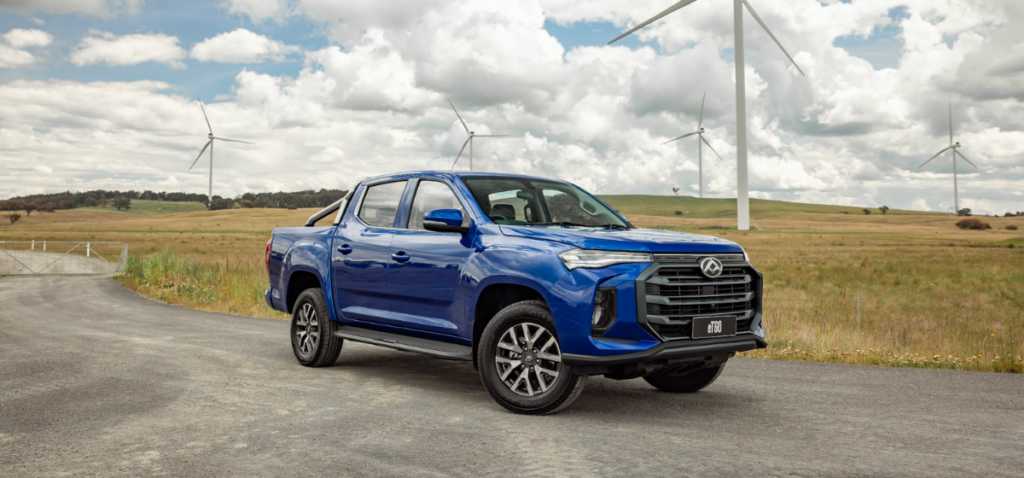 Electric Ute parked in front of wind turbines