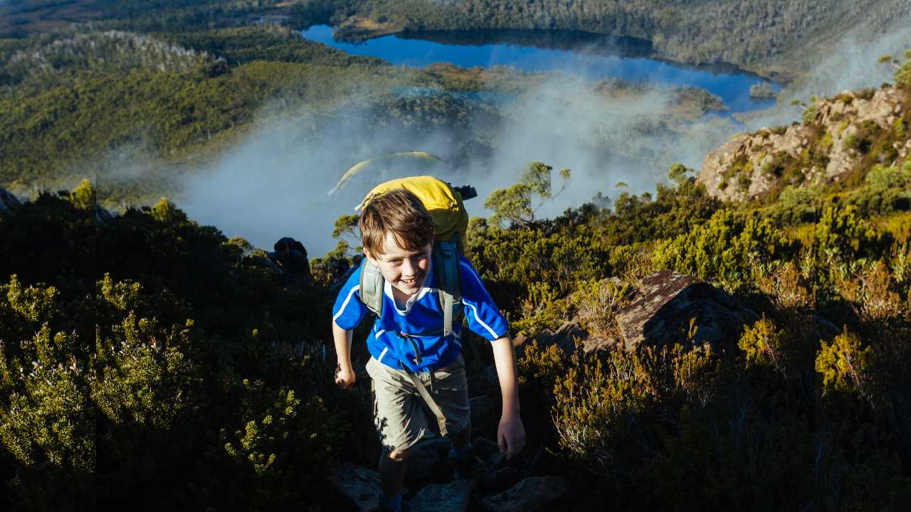 child climbs uphill above a lake